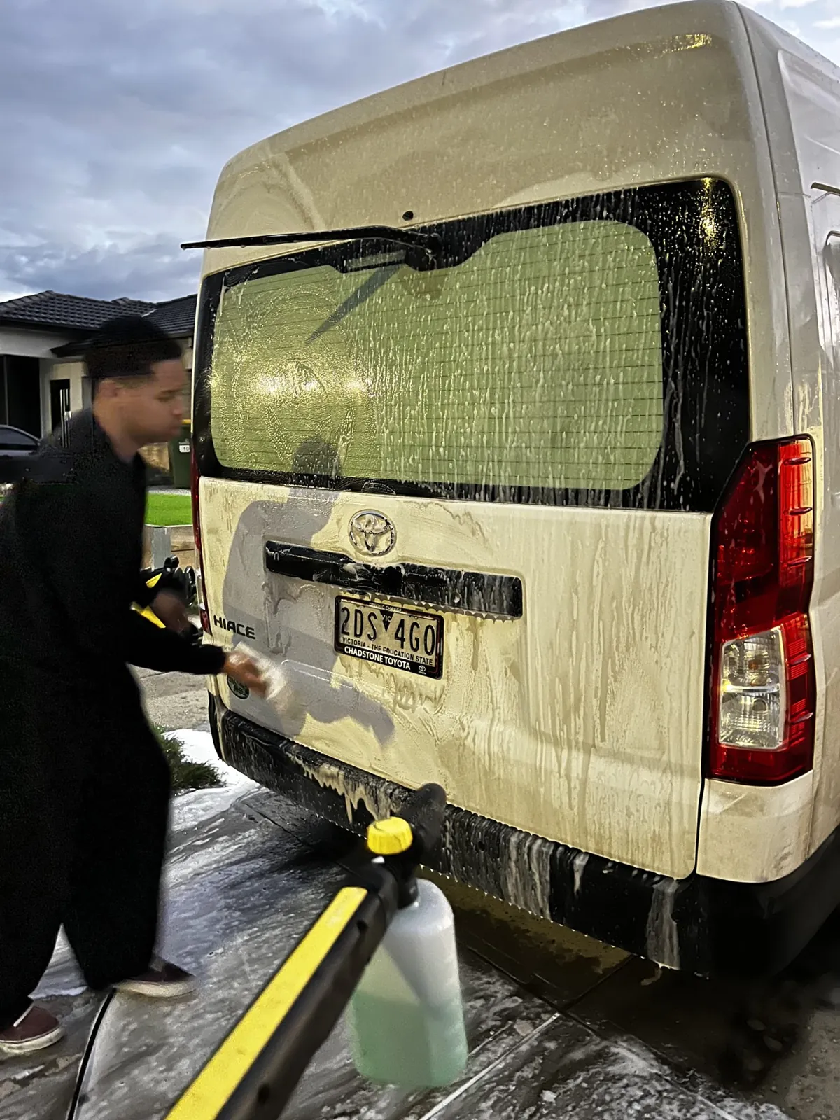 Detailer pressure washing the rear of a Toyota HiAce van