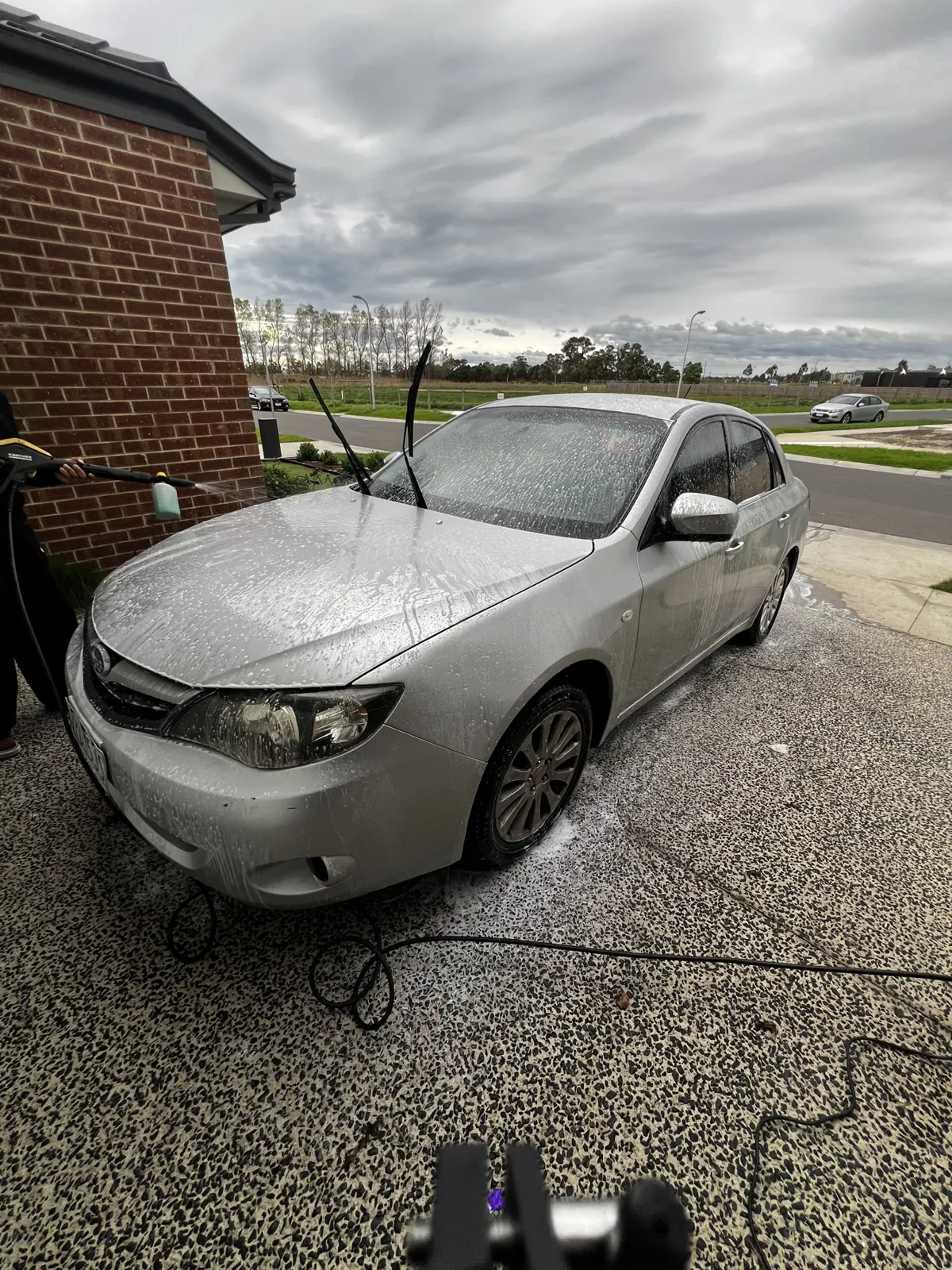 Silver Subaru Impreza covered in snow foam during a maintenance wash