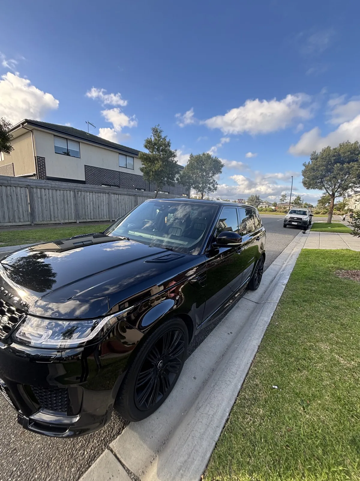 Gloss black Range Rover Sport detailed on a Melbourne driveway under blue sky